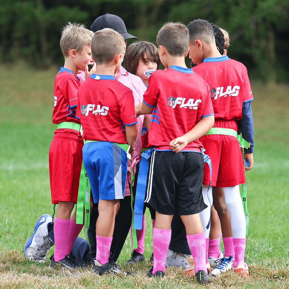 A team in red jerseys huddles up on the field