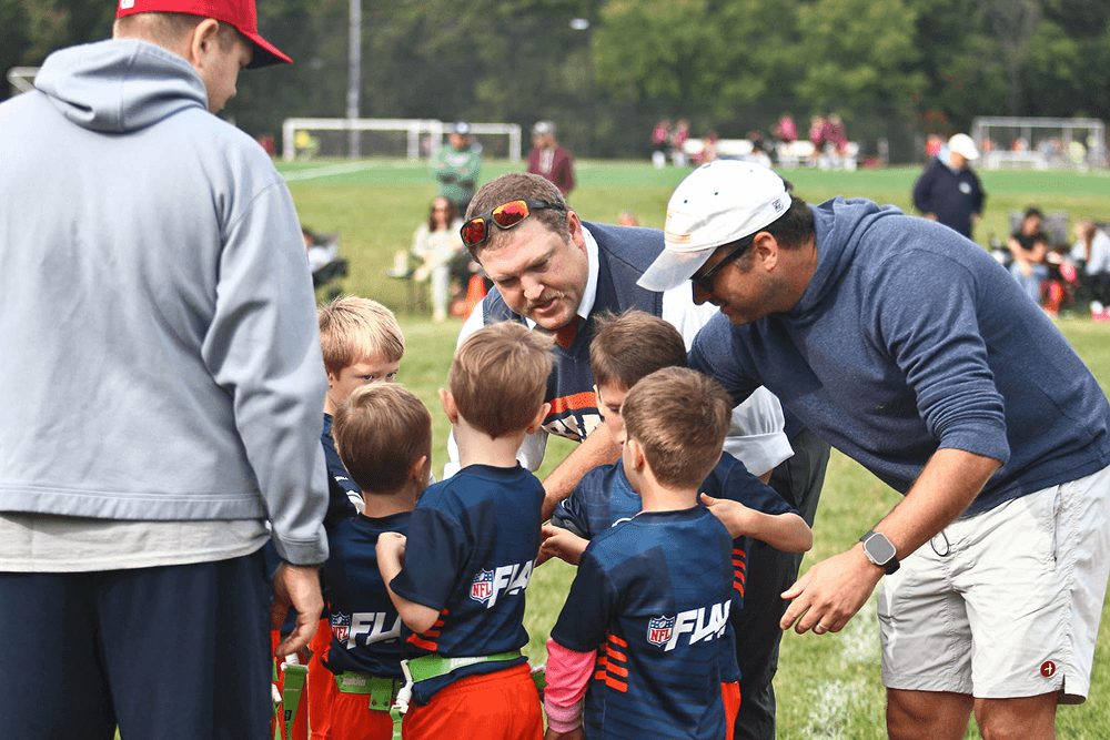 Coaches lean in to talk with their team in a huddle