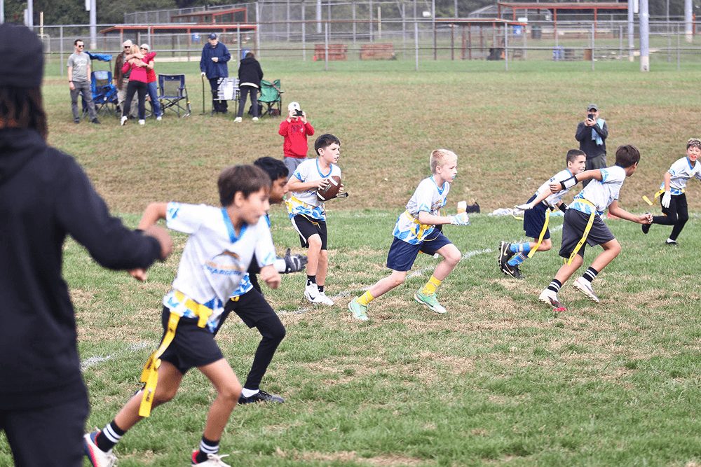 A wide view of a flag game with families on the sideline