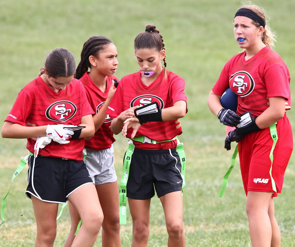 All-Girls players in 49ers jerseys get ready on the sideline